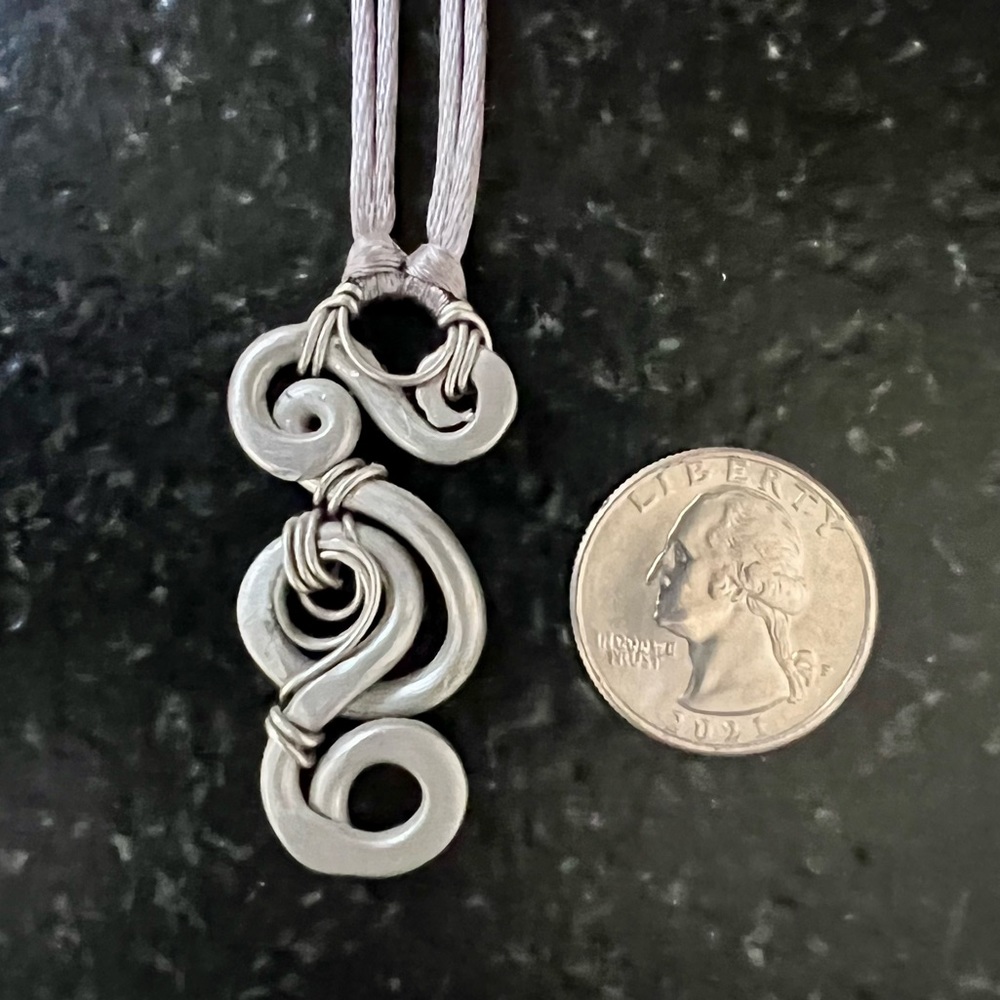 Swirled metal charm from Costa Rica on 18-inch silk cord with hook clasp.
